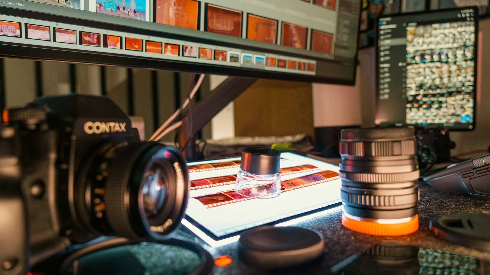 Tavolo di lavoro con negativi sotto la lente e provini in fila sul monitor, lo sguardo che manca alle classifiche dei migliori registi
