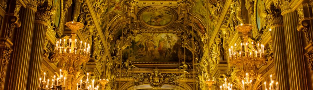 Sala dorata di un teatro barocco con volte dipinte e lampadari accesi, il luogo dove attore e teologo si somigliano