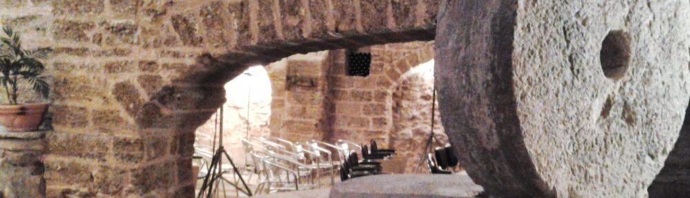 Sedie allineate e cavalletti per le luci sotto la volta in pietra di un frantoio ipogeo a Mesagne, immagine per una rassegna di corti teatrali