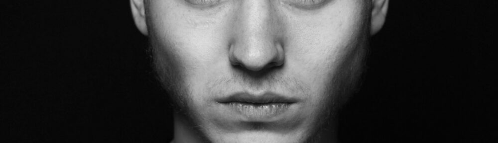 Volto di un giovane uomo senza espressione su fondo nero, immagine per l'articolo su cosa si studia a scuola di recitazione