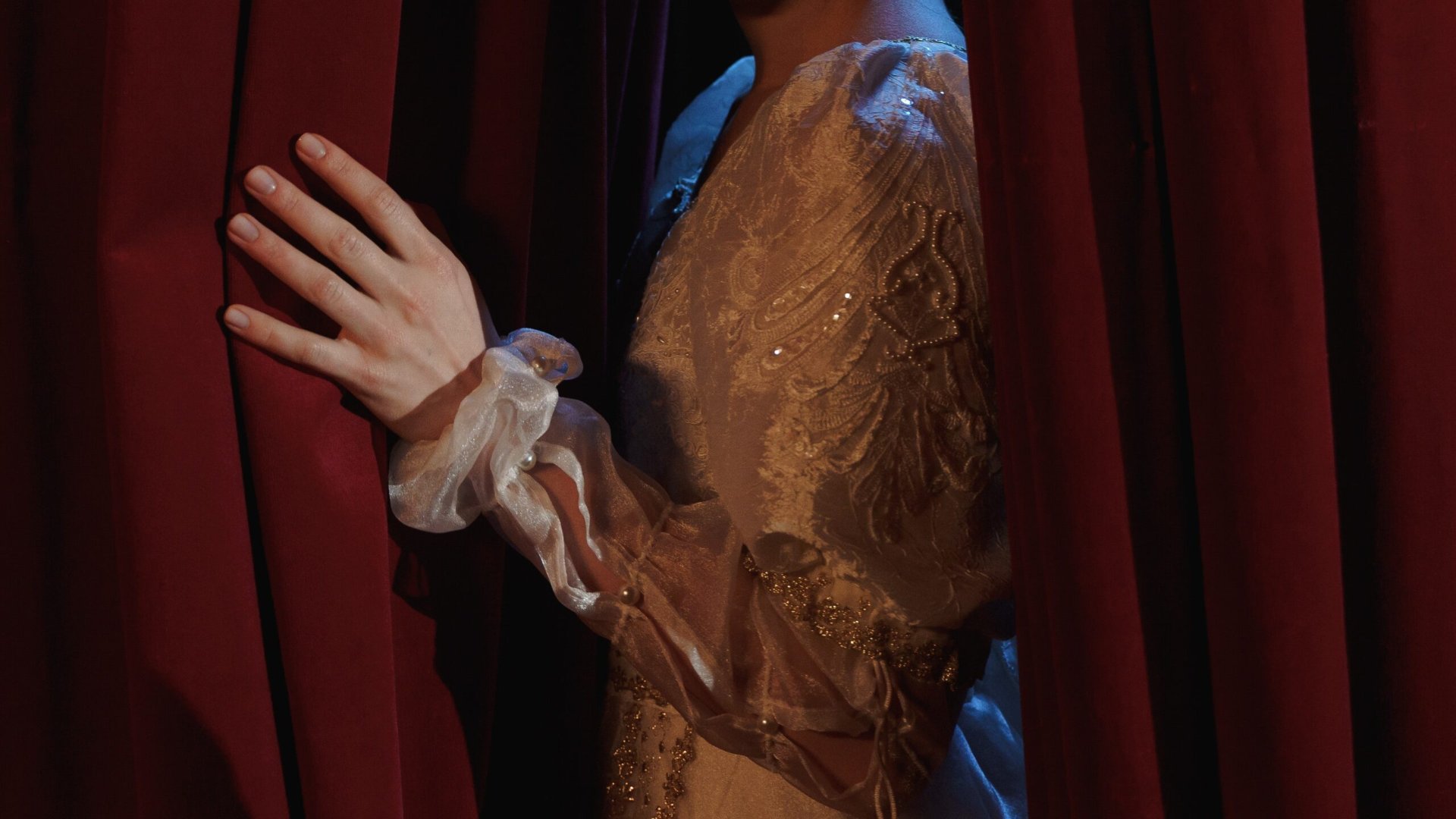 Mano di attrice che scosta il sipario rosso un attimo prima di entrare in scena, immagine per i corti teatrali