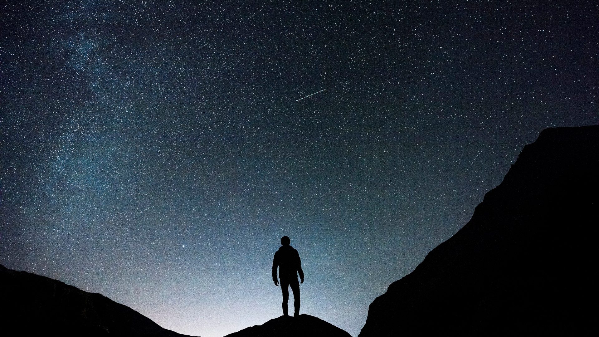Un uomo solo in piedi su una collina guarda il cielo stellato, il canto di Dio nello spazio aperto sopra di lui