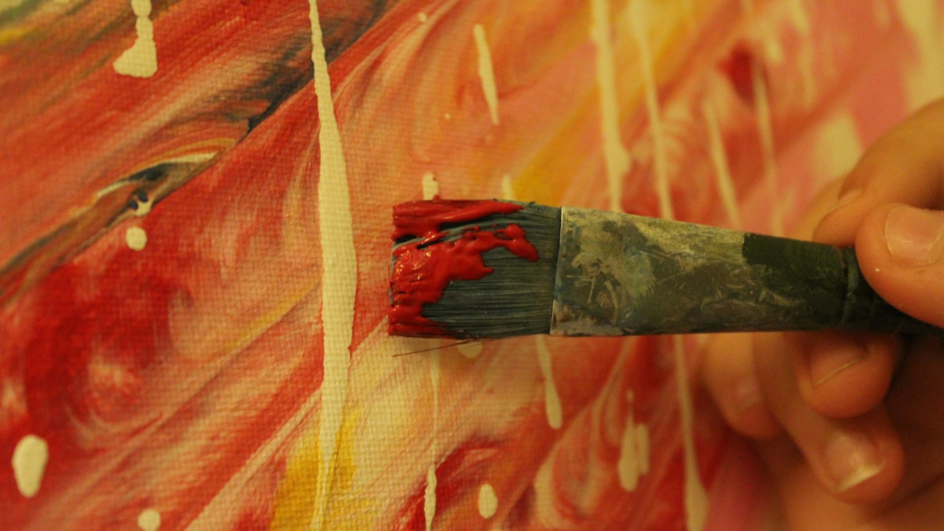 Un pennello carico di colore rosso appoggiato su una tela dipinta, immagine dell'attore come mezzo artista