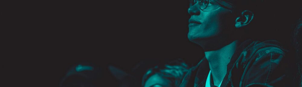 Volti di spettatori assorti nel buio, illuminati dalla luce di uno schermo: il segno che gli attori italiani al cinema lasciano su chi guarda