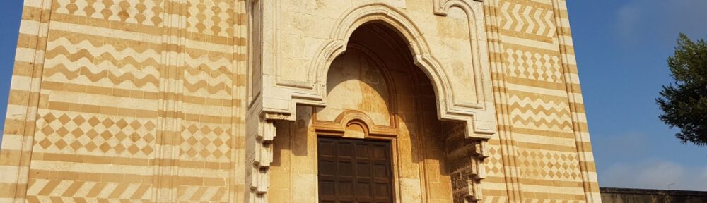 La facciata di Santa Maria del Casale a Brindisi, in fasce di carparo ocra e pietra bianca, con il portale ogivale al centro