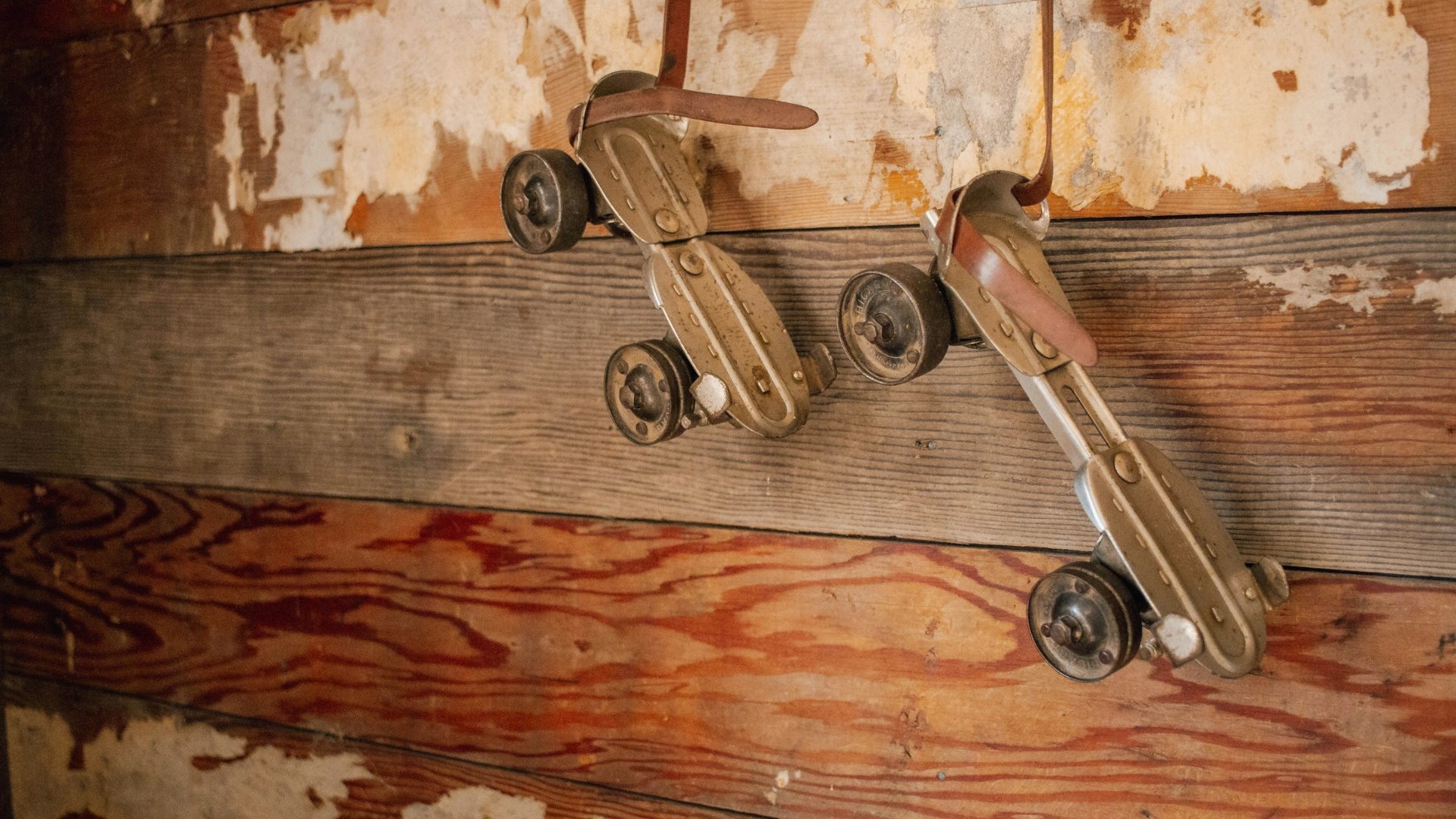 Un vecchio paio di pattini di metallo appesi per le cinghie a una parete di legno scrostato, come i pattini di Giacomo nell'officina
