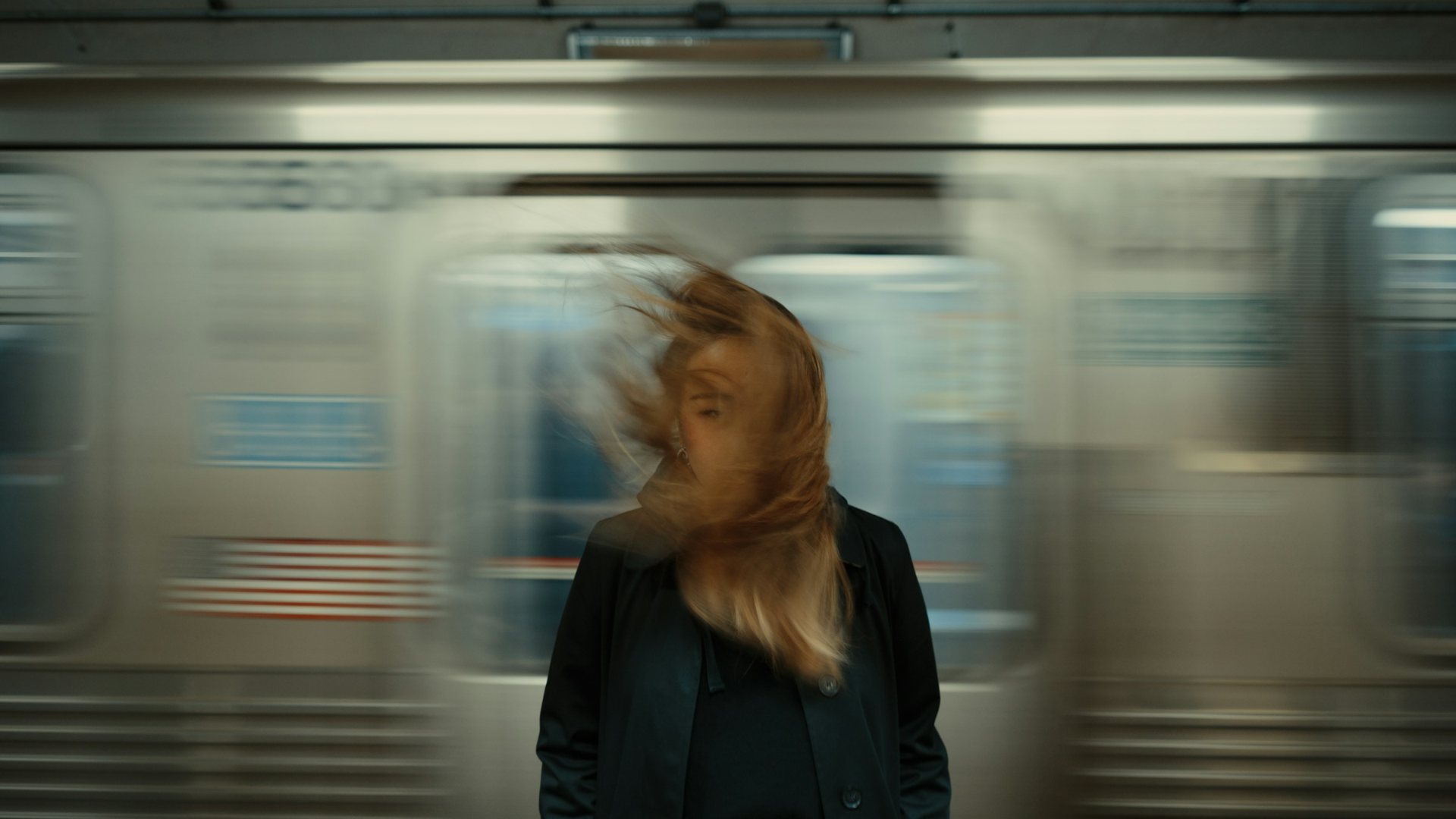 Una donna ferma sulla banchina della metro mentre un treno le sfreccia alle spalle e le scompiglia i capelli: immagine dell'articolo su Stanislav Petrov e sul fermarsi a pensare