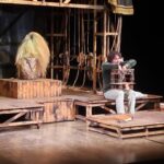 Francesco Montanari in Storia di un cinghiale, variazione su Riccardo III, seduto con un teatrino in miniatura in braccio