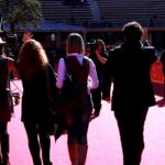 Il red carpet della Festa del cinema di Roma nel 2010, visto da dietro: Giuseppe Vitale in giacca scura saluta con il cast di Come se fosse facile