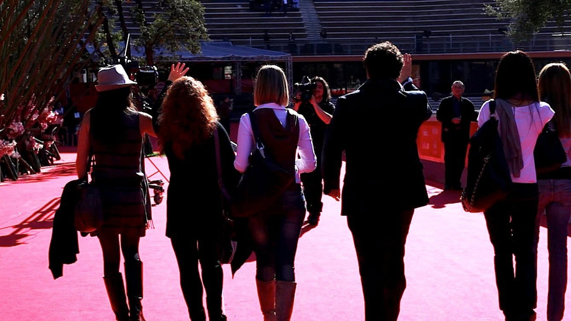 Il red carpet della Festa del cinema di Roma nel 2010, visto da dietro: Giuseppe Vitale in giacca scura saluta con il cast di Come se fosse facile